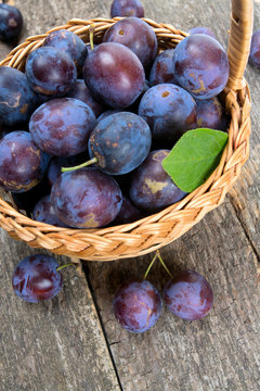 plums in basket on wooden surface