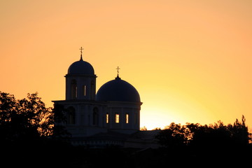 Silhouette of churches on a golden sky and the sun