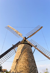Fototapeta na wymiar Old wooden mill against the blue sky