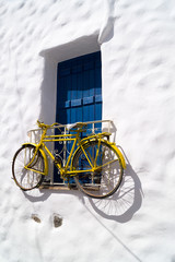 Decorative bicycle hanging from a window in a Greek house on Nax - obrazy, fototapety, plakaty