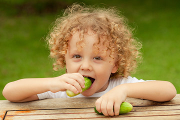 Happy little boy holding a  cucumber. Concept of healthy food. © altanaka