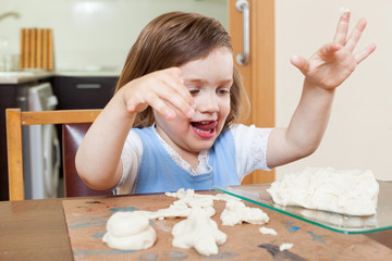 Cute little girl learning to sculpt dough figurines