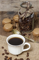 Cup of coffee on hessian napkin. Coffee beans around. Selective
