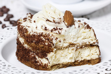 Tiramisu cake on white plate. Wooden background, selective focus
