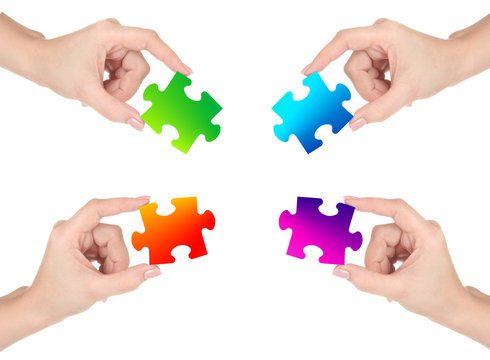 Four hands holding colorful puzzle, isolated on white