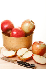 Fototapeta na wymiar Cut Apples by Whole Apples in a Wood Bowl