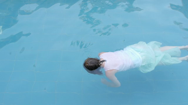 drowned woman body drifting in a swimming pool facing down