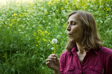 Woman blowing on a dandelion