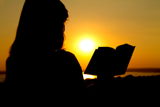 silhouette of a girl reading at sunset