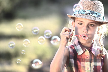 girl in a hat lets soap bubbles
