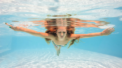 Underwater woman portrait wearing bikini in swimming pool.