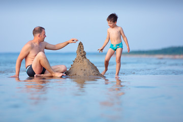 Young father and son building sand castle at beach