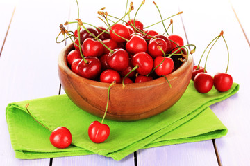 Cherry berries in bowl on wooden table close up