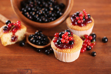 Tasty muffins with berries on wooden table