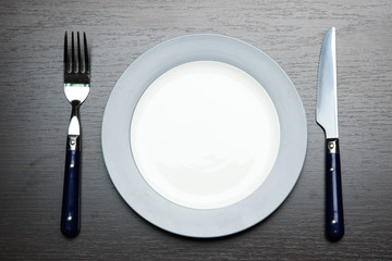 Knife, color plate and fork, on wooden background