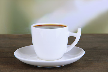 Obraz premium Cup of coffee on wooden table on bright background