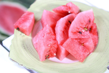 Watermelon slices on plate on table on grass background