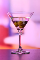 Martini with green olives on table in bar