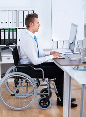 Businessman Sitting On Wheelchair And Using Computer