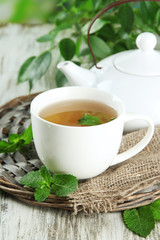 Teapot and cup of herbal tea with fresh mint on wooden table