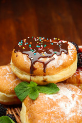 Tasty donuts with chocolate on wooden table