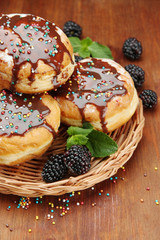 Tasty donuts with chocolate and berries on wooden table