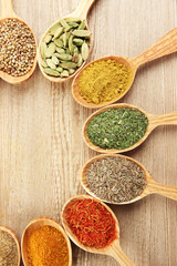 Assortment of spices in wooden spoons on wooden background