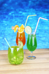 Tasty cocktails on swimming pool background