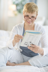 Happy Woman Reading Book On Bed