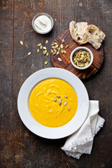 Pumpkin soup in white plate on wooden background