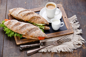 Sandwich with smoked salmon and coffee on vintage slate chalk bo