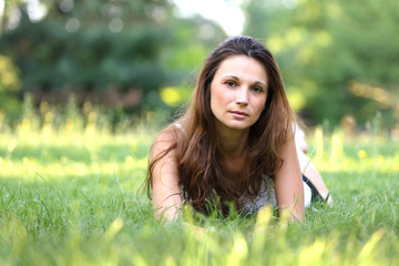 young brunette beautiful girl lying on meadow. outdoor portrait.