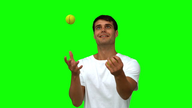 Man dribbling with tennis balls on green screen