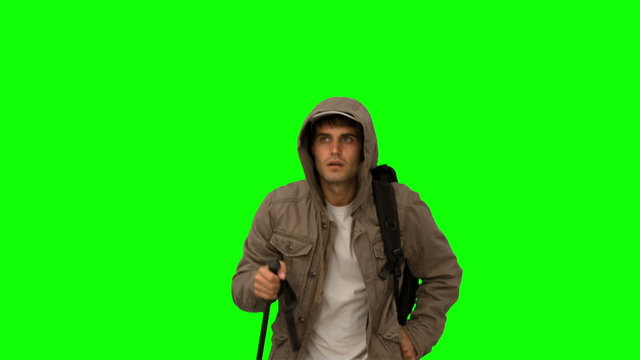 Man with a coat trekking on green screen