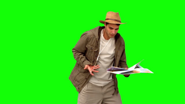 Man with a map and a compass orienteering on green screen