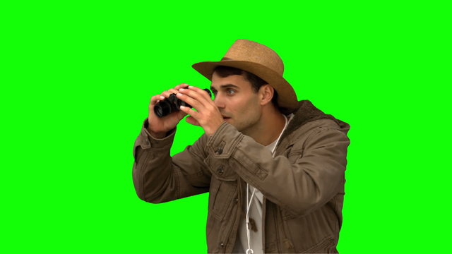 Man wearing a coat using binoculars on green screen