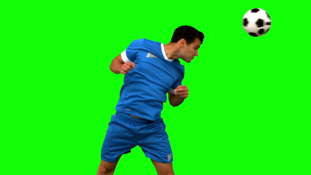 Attractive man heading a football on green screen