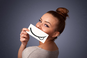 Pretty young girl holding white card with smile drawing