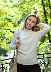 The beautiful woman in a white sweater on the bank of the lake