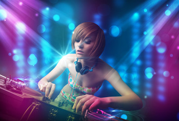 Obraz na płótnie Canvas Dj girl mixing music in a club with blue and purple lights