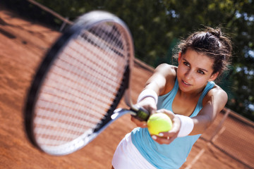 Young girl catching a ball in tennis court
