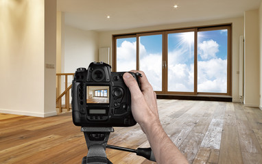 Man photographing empty living room with digital camera - obrazy, fototapety, plakaty