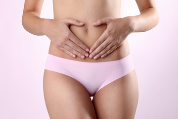 Woman's hands on stomach on white background