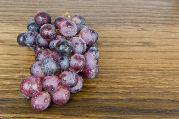 Purple grapes on oak shelf sprinkled wet