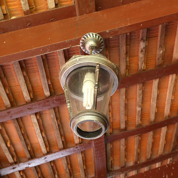 old lamp hanging from the ceiling under a wooden canopy