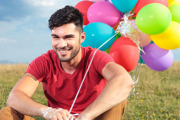 closeup of seated casual man with balloons