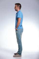 side of a casual man with hands in pockets