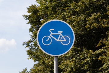 Blue bicycle lane sign with sky and trees background