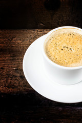 Closeup cup of espresso on old wooden table over grunge backgrou