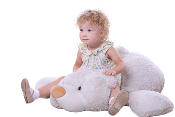 Little baby sitting on the white toy bear.